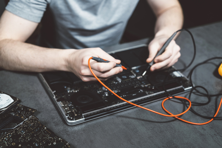 Engineer or technician repairing electronic circuit board with soldering iron for article on learning downtime