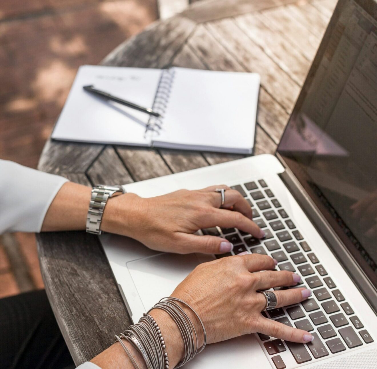 Image is a photo of a female at a laptop computer typing, with a small notebook to the left and a pen laying over the paper. Image used for SmartBrief blog post titled: "5 key elements for effective headlines"