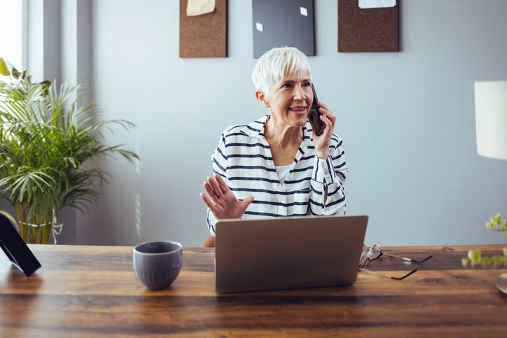 Happy older woman using mobile phone and smiling while sitting at home during the day. for article on parent communication