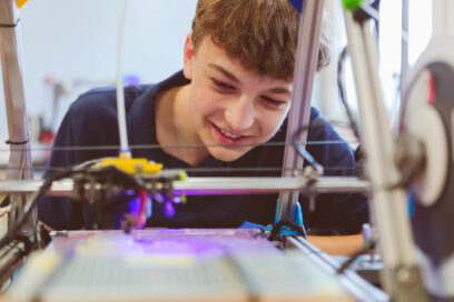 Close up of Gen Z  teenage boy watching three-dimensional printing in contemporary laboratory. for article on invention education