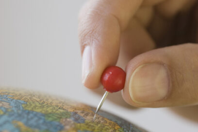 Close up of pin marking place on globe for article on happiness