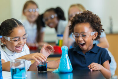 Diverse private school classmates are excited as foam overflows from beaker during chemistry experiment. for science article