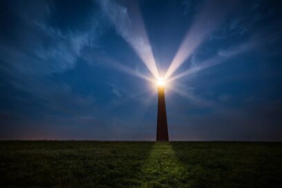 Image of a lit up lighthouse at night along a shore, viewed from the land side. SmartBrief story about how brands can contribute to national healing