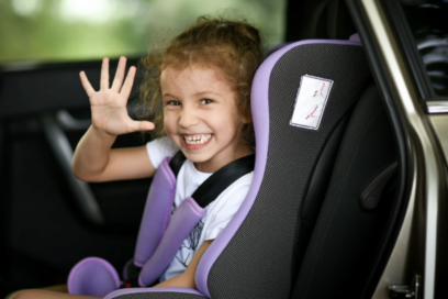 Small chlid in car seat waving out the car door